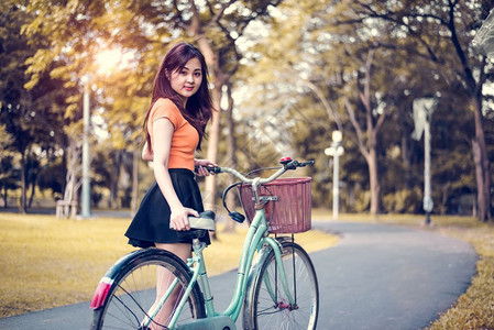请享用亚洲人秋天公共园中的亚洲妇女肖像配有自行车人民和生活方式概念的放松娱乐和活动主题背景图片