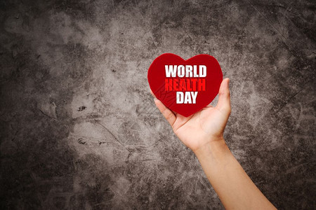 商业身体约定世界健康日妇女用红心在黑背景上握着红心图片