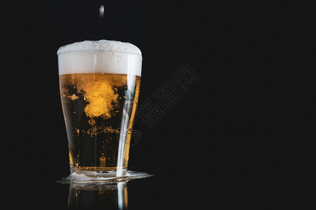 倒了酒吧品脱泡沫啤倒在玻璃杯上黑色背景有复制空间图片