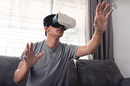 紧张的一个快乐男人坐在沙发上戴着3D虚拟真人眼镜激动瘾君子图片
