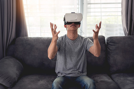 长椅虚拟的运动一个快乐男人坐在沙发上戴着3D虚拟真人眼镜图片