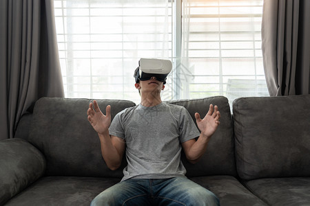 足球损失一个快乐的男人坐在沙发上戴着3D虚拟真人眼镜观看图片