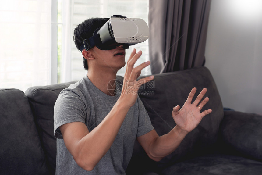 情感胜利一个快乐的男人坐在沙发上戴着3D虚拟真人眼镜目标图片
