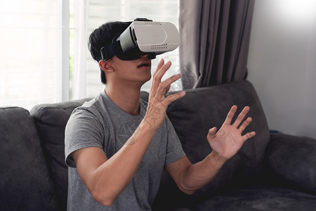 情感胜利一个快乐的男人坐在沙发上戴着3D虚拟真人眼镜目标图片