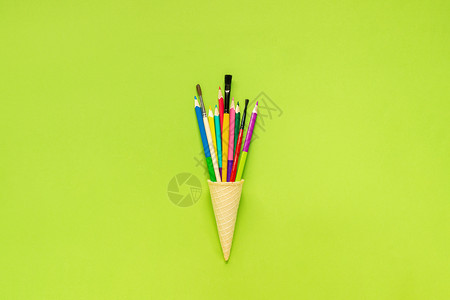 冰淇淋模板最佳平坦的知识彩色铅笔在绿纸背景的华夫冰淇淋甜锥中漆刷绿色纸背景的概念教育或回到学校平板版明信片字母文本或设计最优视图模板花纸面背景