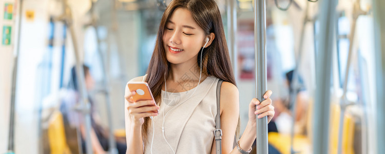 地铁封面旅行班纳网页或封面模板亚洲青年女乘客在地铁火车站日本钦那朝韩生活方式休闲和日常生活中使用智能移动电话并监听音乐以及新南朝鲜人的生背景