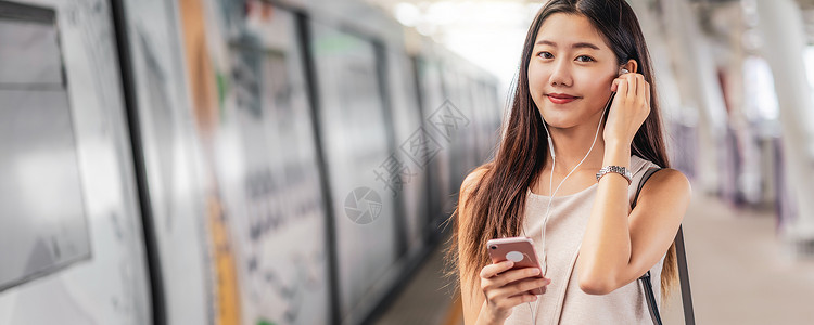 地铁封面娱乐聪明的班纳网页或封面模板亚洲青年女乘客在地铁火车站日本钦那朝韩生活方式休闲和日常生活中使用智能移动电话并监听音乐以及新南朝鲜背景