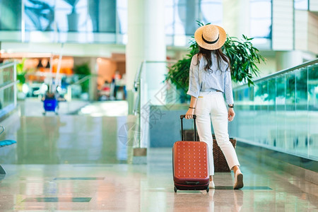 带帽子情手提箱飞机场护照在国际带行李的年轻女子带着行李在机场休息室等待飞机的公司乘客设计图片
