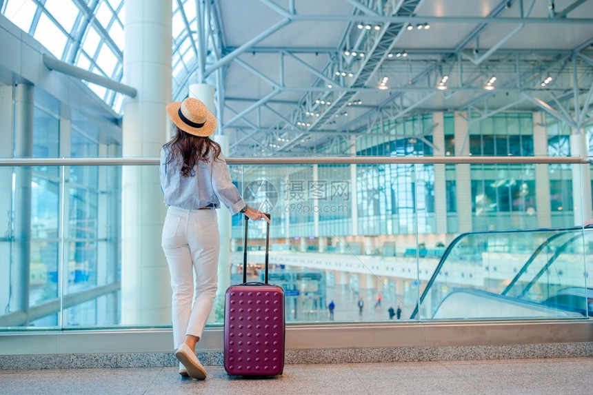 游客国外假期戴帽子的年轻女带着行李在国际机场航空公司乘客在机场休息室等待飞机戴帽子的年轻女带着行李在国际机场图片