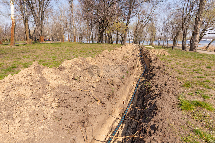 层沟渠乌克兰基辅纳塔卡公园靠近河水系统的树木下乌克兰基辅纳塔卡公园地面灌溉系统铺设管道的灌溉系统子安装行业图片