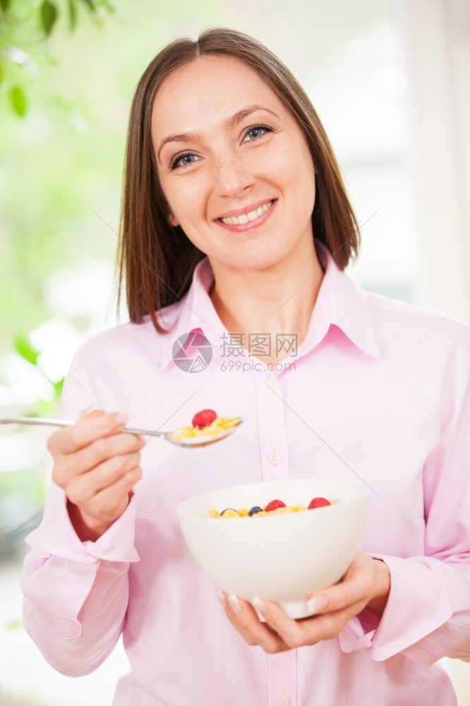 素食主义者笑的黑发女人肖像她拿着一碗有玉米片子和浆果的碗微笑可口图片