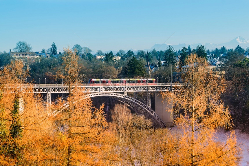 塔火车在一条河桥上航行背着瑞士伯尔尼阿卑斯山脉的景象传统图片