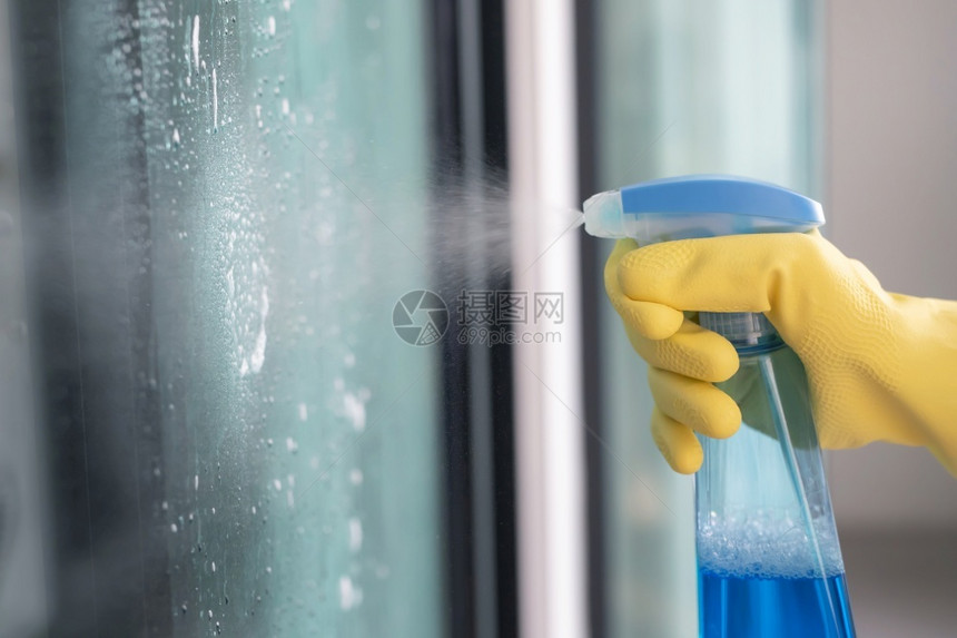 家庭雇员使用喷雾清洁玻璃代理人卫生图片