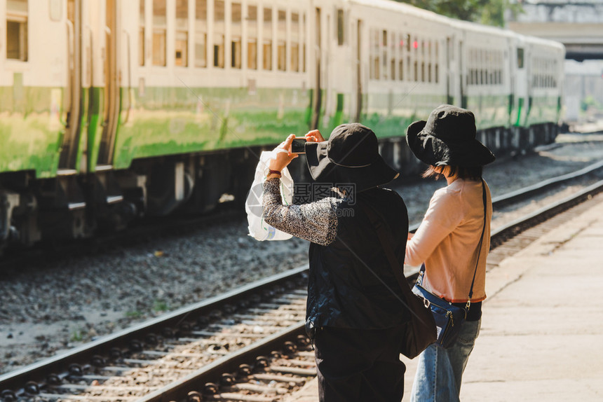 白种人年轻的旅游女在火车站拍旧列的照片图片