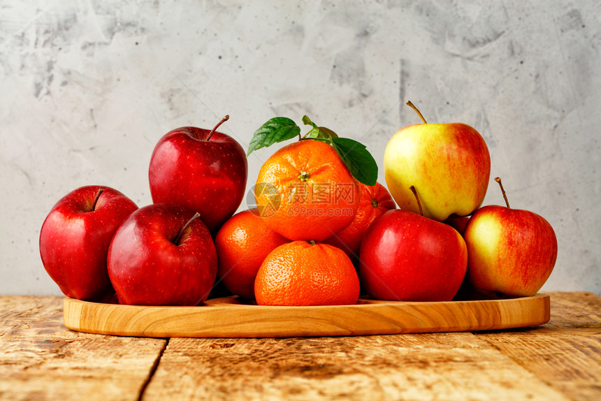 绿色红成熟的苹果和绿叶橘子放在灰色混凝土背景的旧木桌上托盘带有复制空间的图像红色成熟的苹果和绿叶橘子放在灰色混凝土背景的旧木桌上图片