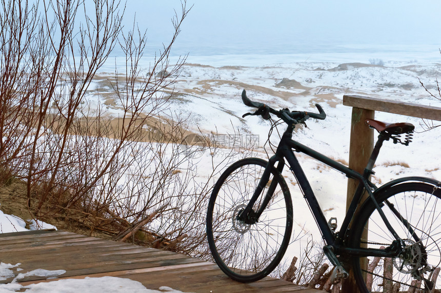 运输雾霭沙丘中的黑色旅行自车山顶上的黑色自行车沙丘背景上的自行车高的雾蒙的沙丘中黑色旅行自车在沙丘上骑自行车海滩蓝色的图片