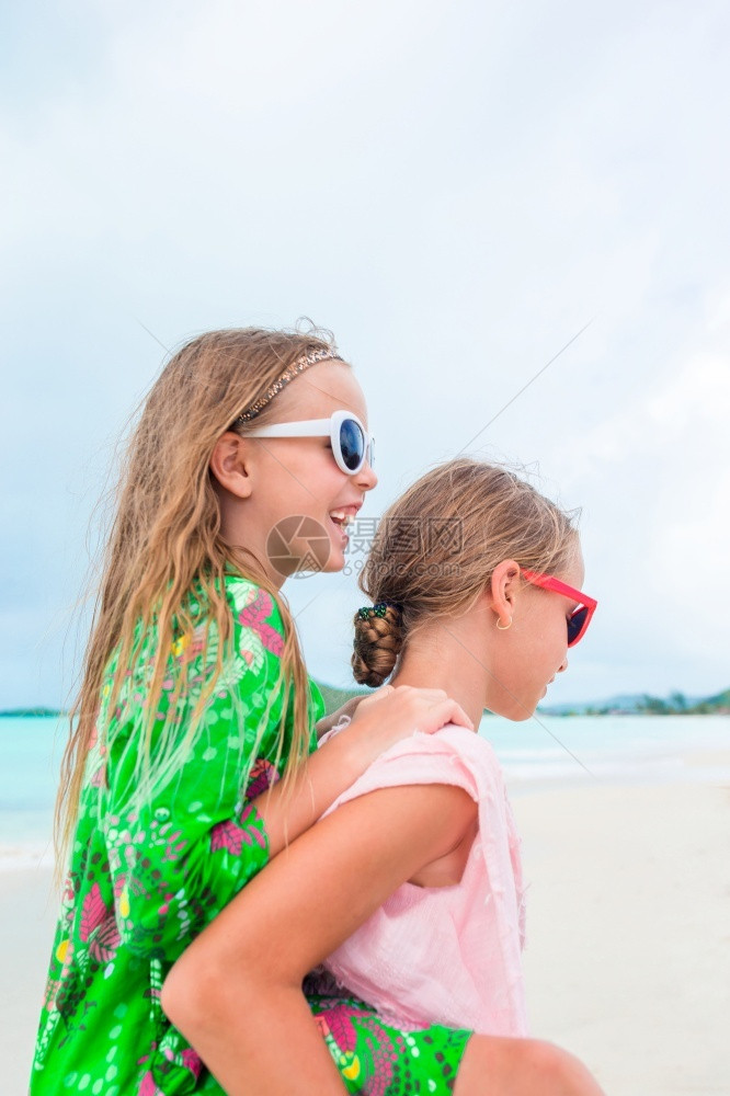 娱乐海岸线假期小女孩在热带海滩玩得开心在浅水区一起玩暑假在海滩的可爱小姐妹两个快乐的小女孩在热带海滩玩得很开心图片