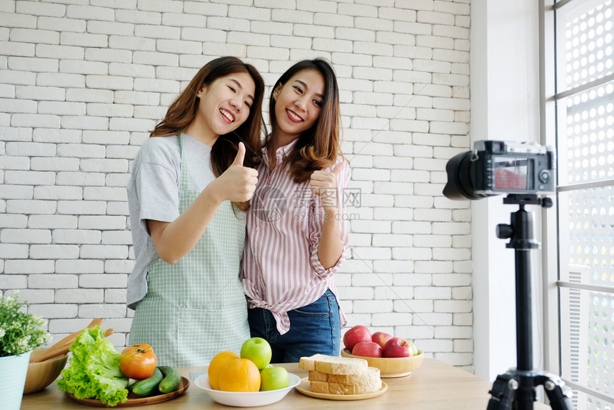 有创造力的尽管两位年轻女食品博客在录制视频vlog概念人食物及科技通讯时谈论并鼓起大拇指美食图片