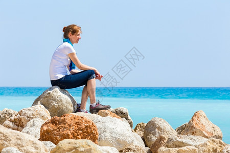 旅游欧洲中年妇女作为游客在蓝海平面岩石上观光的欧洲中年女士海景图片