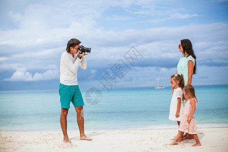 男人在海滩上给家拍照男在给家拍照白种假期女儿图片