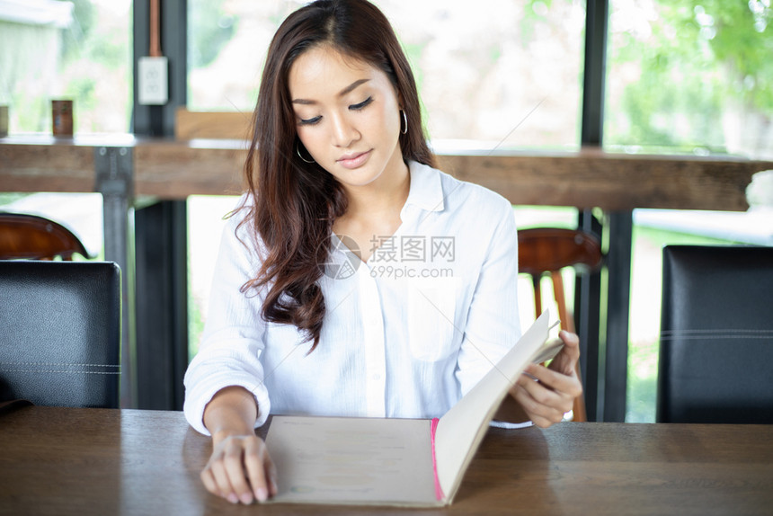 商业亚洲女开放菜单在咖啡厅和餐点菜并微笑快乐时光顾客为了图片