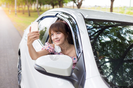 女淑流动在白色车窗上手持智能机的妇女图片