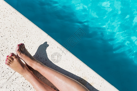 裁剪吸引人的健康女腿树种游泳池边图片