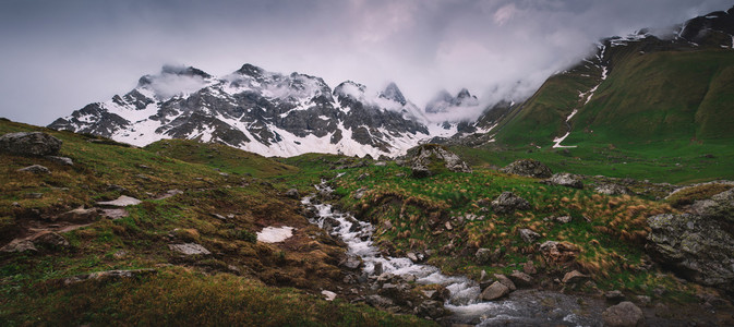 谷山格鲁吉亚卡夫索里提周围有雪峰新春绿草和美丽的云雾全景国民图片