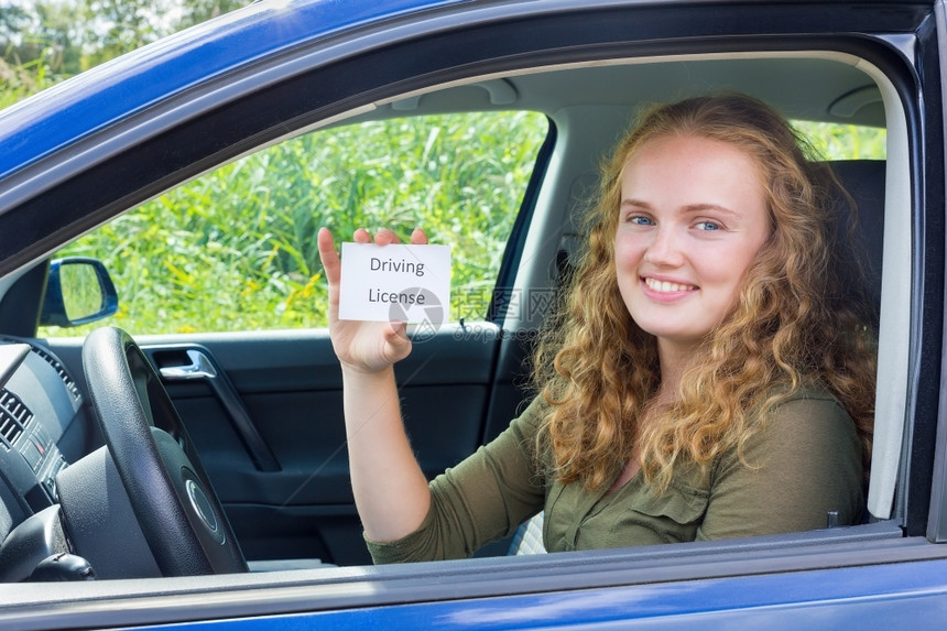 快乐荷兰持有汽车卡驾驶执照的年轻欧洲青妇女安全的图片