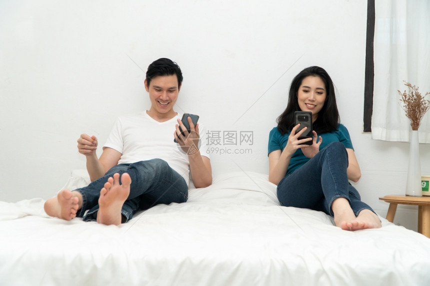 亚洲情侣在床上时常使用智能手机但不要互相关心对方的系问题和不忠概念关系问题和不忠的概念用途说谎家庭图片
