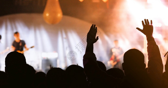 人们夜晚店音乐会群众在节日观看后举手向明亮的舞台灯升起图片