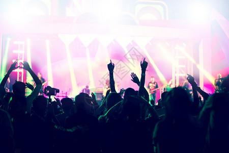 庆典音乐会群众在节日观看后举手向明亮的舞台灯升起青年乐趣图片