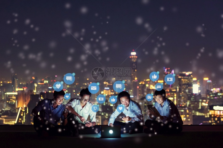 人们沟通利用智能手机平板电脑和笔记本工作或玩社交媒体的亚洲人群以及夜间有天线城市的高楼屋顶站点网社交络技术概念社交媒体和网络等媒图片