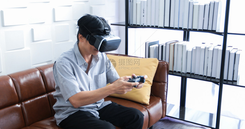 长椅乐趣俏皮亚洲高龄男子使用平板和虚拟现实模器在客厅玩游戏并家里感到幸福的生活方式老年人家庭概念利用平板和虚拟现实模器图片