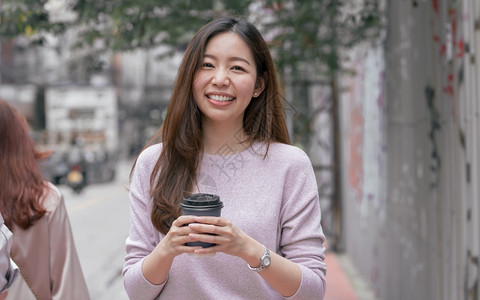 亚洲美丽的女在冬季走街边喝咖啡时饮的亚洲美丽女种族的微笑复制空间图片