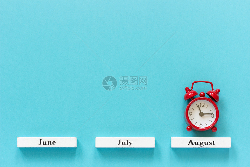 木制的喜庆典木制日历夏季月份和8在蓝色背景上的红闹钟概念八月时间图片