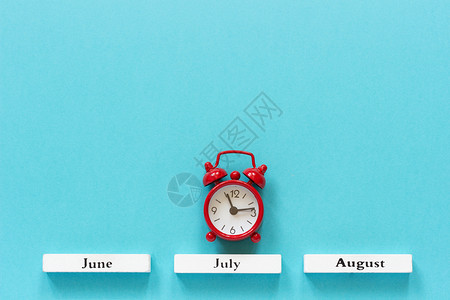 古朗月行木日历夏季月份和7在蓝色背景上的红闹钟概念月时间木制的最小季节设计图片