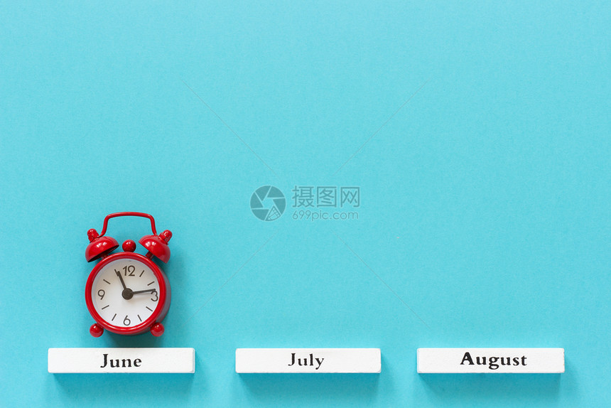 好的木制日历夏季月份和6在蓝色背景上的红闹钟概念月时间季节铺设图片