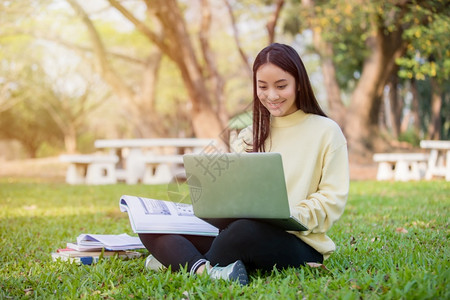 在户外草坪上使用笔记本电脑学习的女生图片