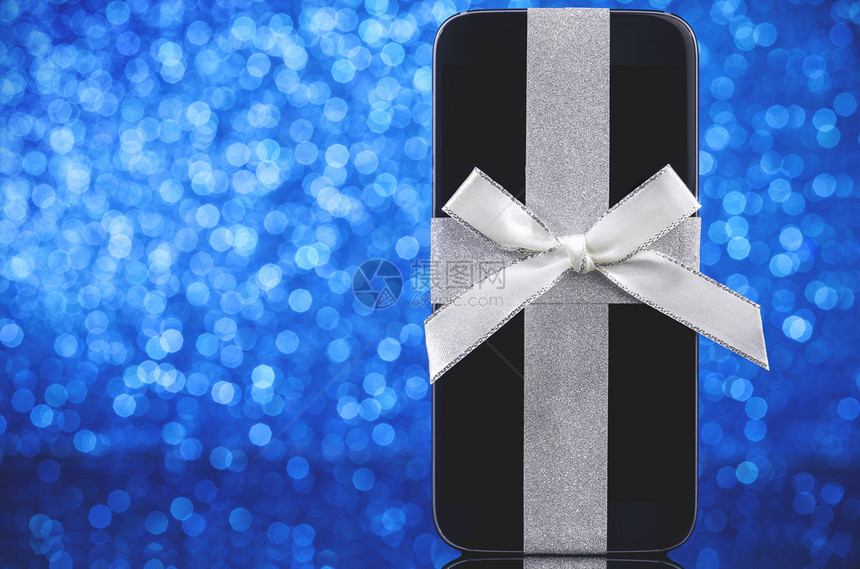 礼物蓝色的背景黑玻璃桌上圣诞树智能手机蓝底面的黑色玻璃桌移动的图片