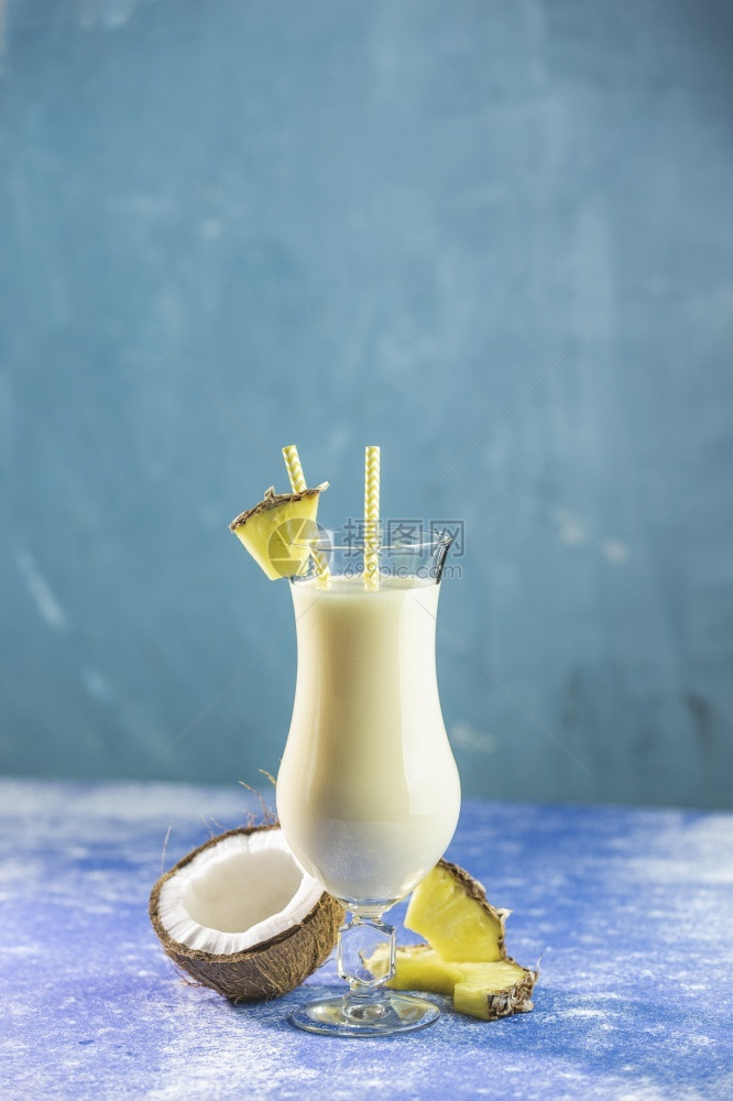 可乐达果汁以蓝混凝土背景配上一片菠萝装饰的冰冻PinaColada加勒比传统鸡尾酒杯奶昔图片