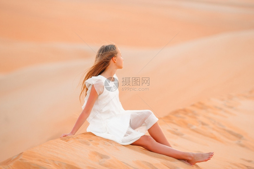 联合的荒凉白色在沙丘度假时穿白色裙子的漂亮女孩在阿拉伯联合酋长国沙漠中穿着白色衣服的美丽沙漠女孩在丘中阿拉伯联合酋长国沙漠中的丘图片