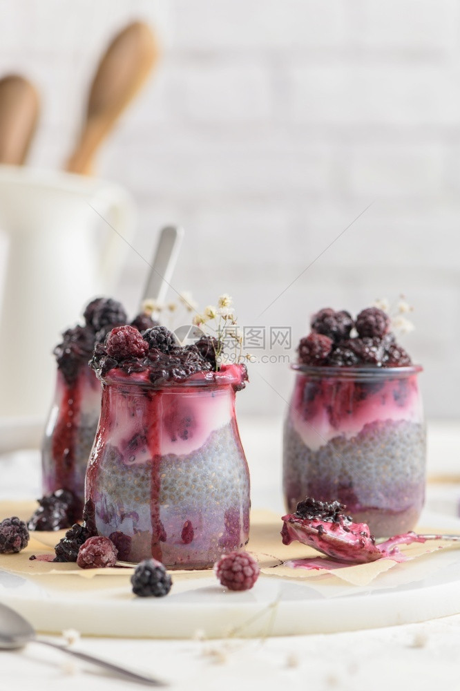 吃早餐加黑莓的Chia布丁在白桌上的玻璃罐中三块食物图片