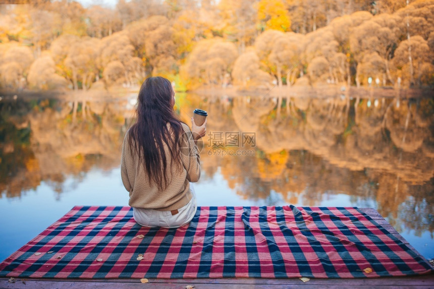 温暖的保持季节秋天公园美丽的女孩享受着湖瀑布概念的风景秋日公园喝咖啡的漂亮女人图片