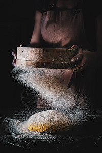 摄影面团女人通过筛子选面粉以制作包黑暗的情绪创意形象烘烤图片