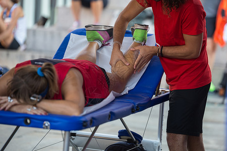 手动按摩仪按摩放松运动员腿部的理疗师背景