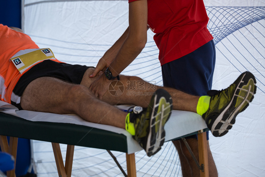 按摩运动员腿部的理疗师图片