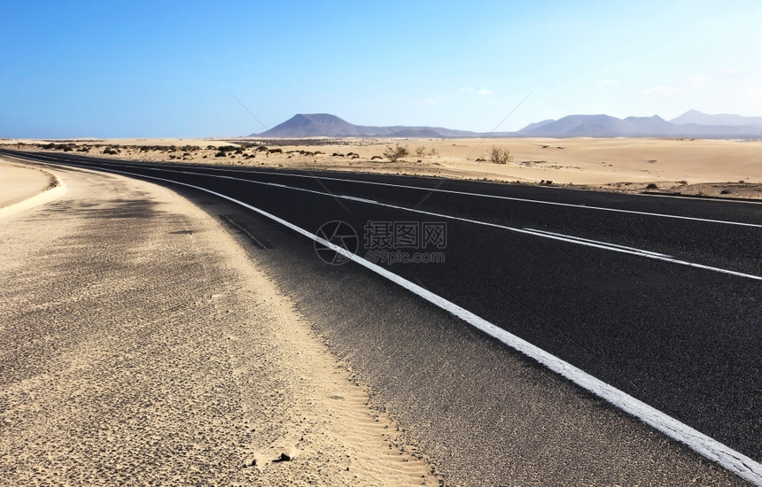 在西班牙加那利群岛Fuerteventura经过具有火山背景的Corralejo沙丘的通风公路夏天运输景观图片