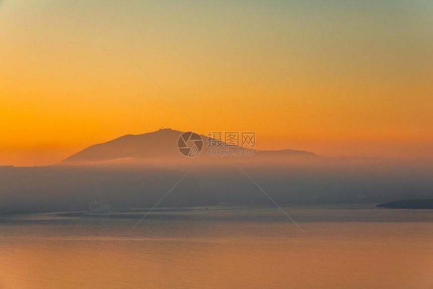 日落后海平面的静橙色天空和雾在山上岸边夜雾过山坡梦幻般的紫色晚上图片