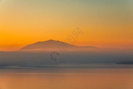 日落后海平面的静橙色天空和雾在山上岸边夜雾过山坡梦幻般的紫色晚上图片